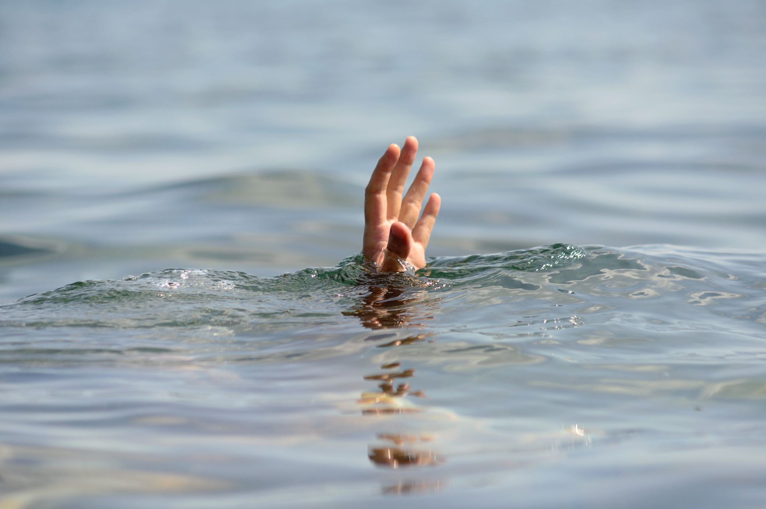 Person underwater reaches out hand about the surface
